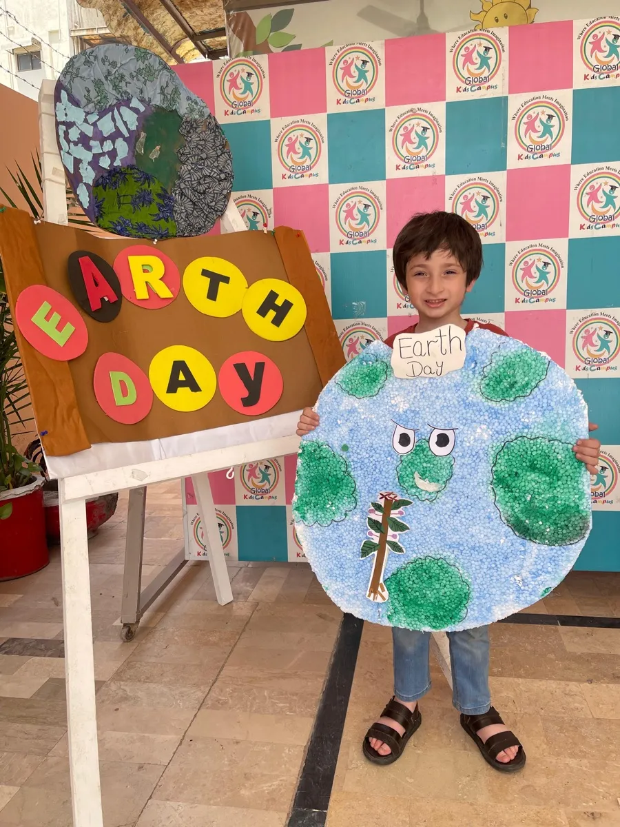 Student proudly displaying Earth Day project at Global Kids Campus Lahore